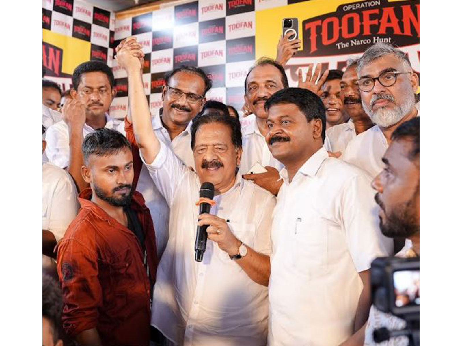 Kerala Home Minister Ramesh Chennnithala holding up the hand of a migrant labourer at Kandanthara Bhai Colony at Perumbavoor. Benny Behanan MP, Manoj Moothedan MLA also seen