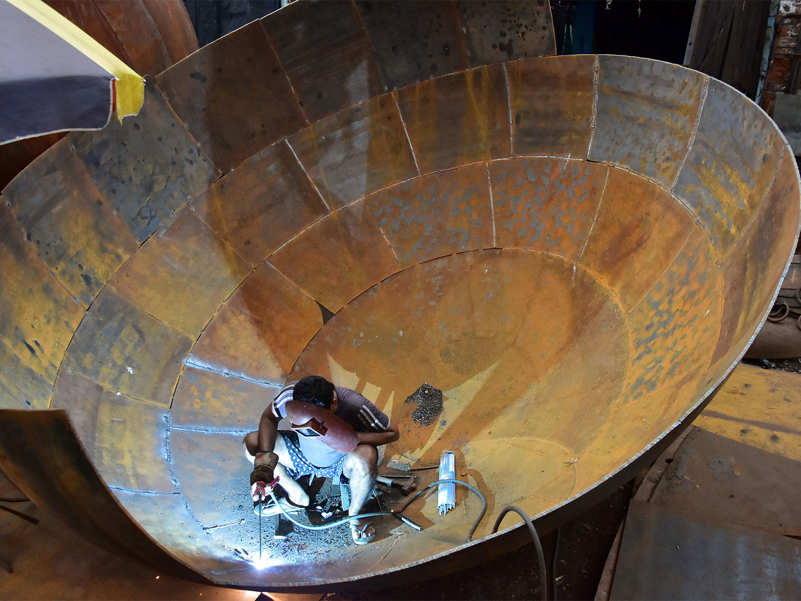 A labourer welding a giant iron pot at an iron factory in Kolkata (File Photo/ANI)